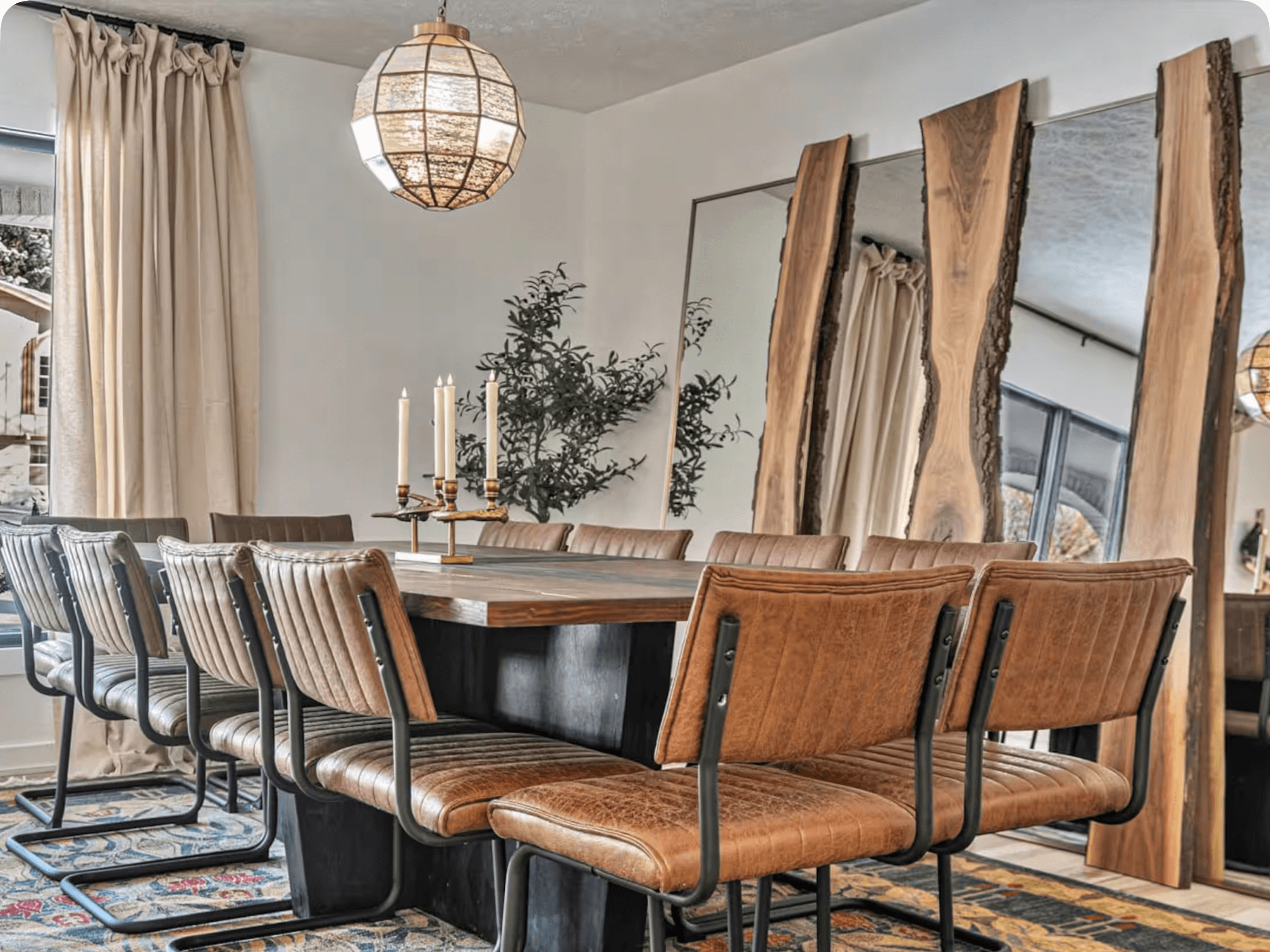 A dining room with a live-edge table, leather chairs and full-height wood-framed mirrors